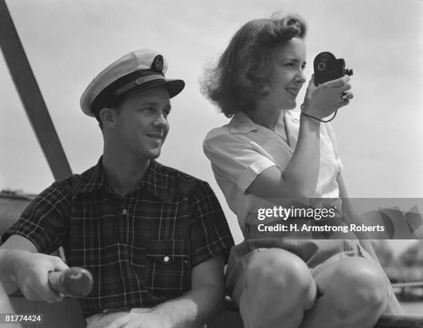 couple on sailing boat, man holding tiller, woman filming with movie camera. (photo by h. armstrong roberts/retrofile/getty images) - retrofile foto e immagini stock