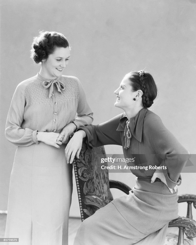 Two women sitting on chair, chatting and gossiping.