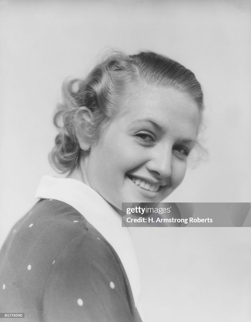 Young woman with curly hair, looking over shoulder.