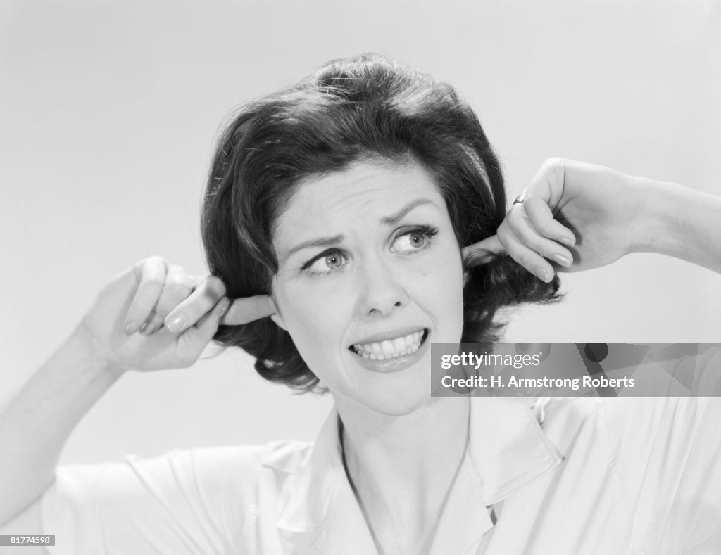 Woman sticking fingers in her ears.