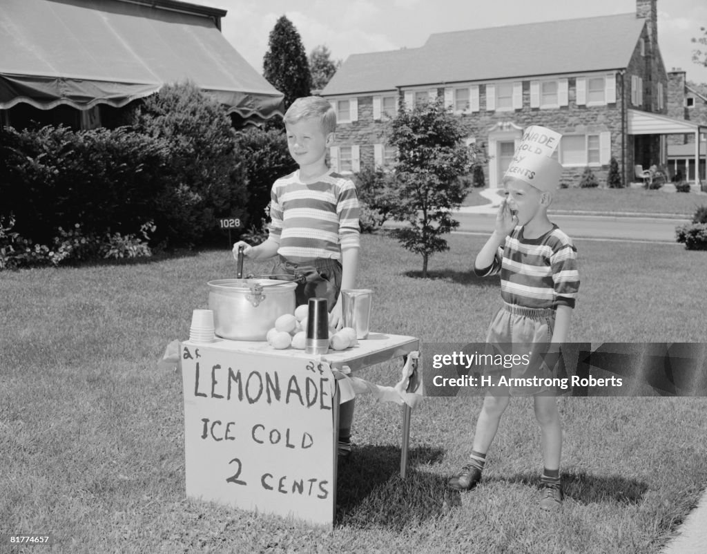Boys on lawn selling lemonade.