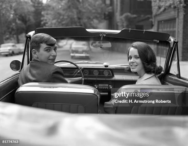 couple in convertible, smiling, looking over shoulders, portrait. - anos 60 imagens e fotografias de stock
