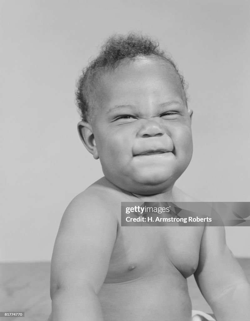 African-American baby squinting eyes and scrunching up face.