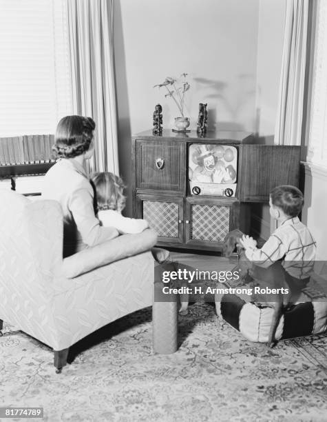 mother and children watching television. - 50s tv family stock-fotos und bilder