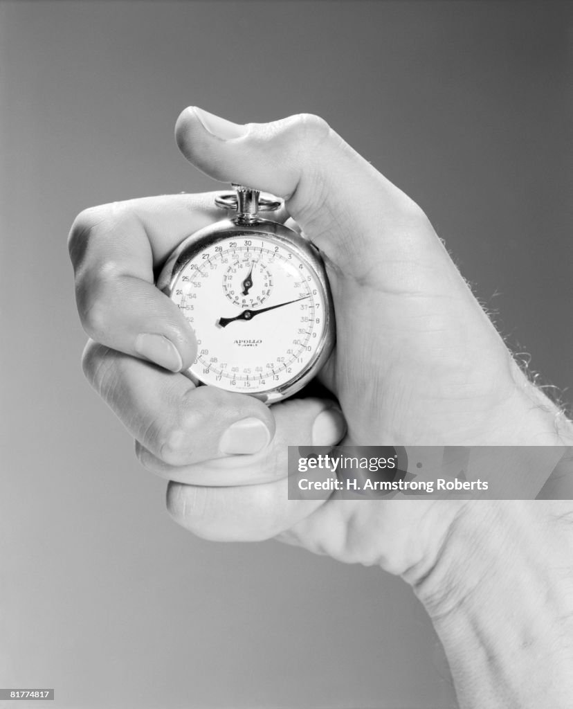 Close up man's hand using stop watch indoor.