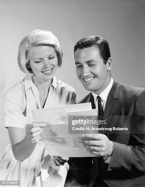 husband and wife homeowners looking at mortgage and smiling. - couple at bank fotografías e imágenes de stock