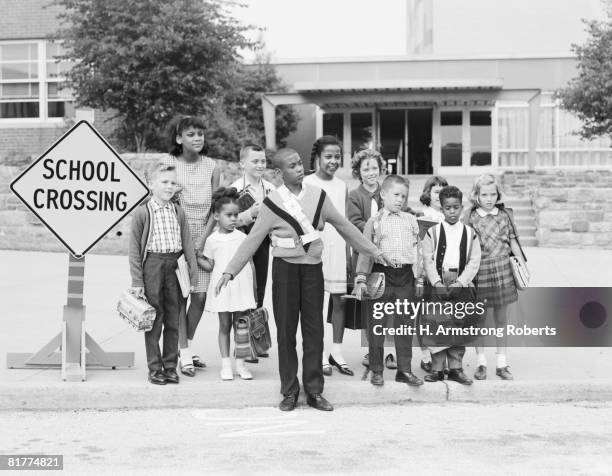 boy safety guard with students at school crossing curb. - placa de travessia de crianças - fotografias e filmes do acervo