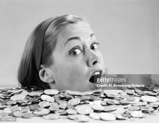 woman pulling funny face, up to her neck in coins. - ahogar fotografías e imágenes de stock