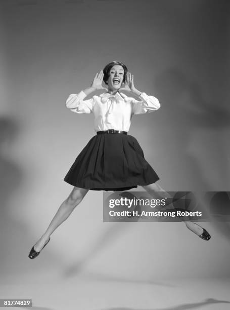 woman doing cheerleader jump, hand up to mouth, yelling and screaming. - cheerleader photos stock pictures, royalty-free photos & images