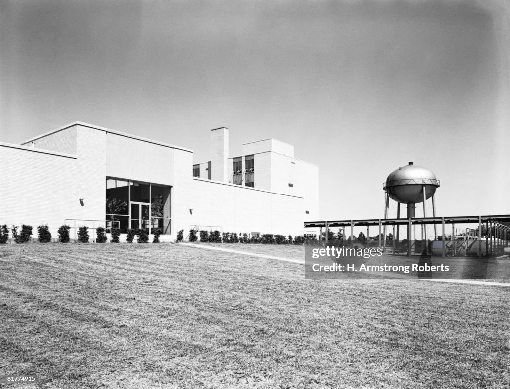 Water purification plant building, with water tower and well maintained grass lawn.