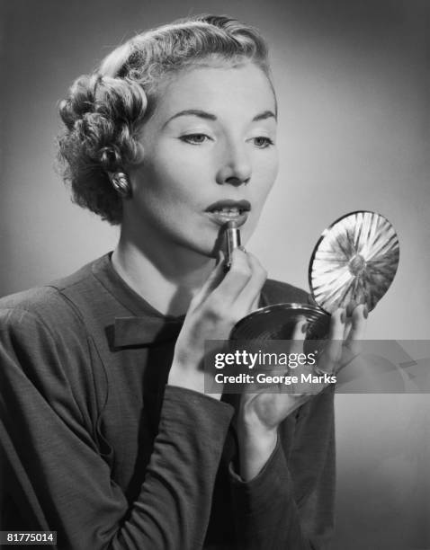 a woman applying her lipstick with the aid of a powder compact, circa 1955. (photo by h. armstrong roberts/retrofile/getty images) - retrofile foto e immagini stock