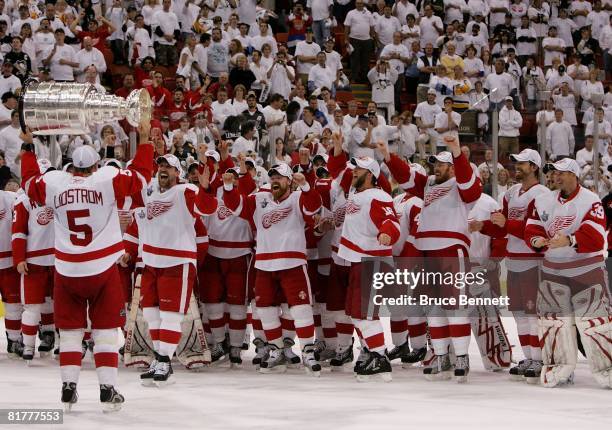 Nicklas Lidstrom of the Detroit Red Wings hands off to Dallas Drake as they celebrate with the Stanley Cup after defeating the Pittsburgh Penguins in...