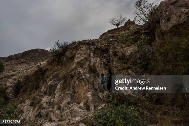 Member of the Afghan Local Police walks out of a cave where allegedly members of ISIS-K stored weapons near the area where the United States dropped...