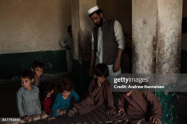 Mir Jamar, a father of 9, watches his family inside the remains of an old Soviet hotel where they have been living for the past two years, on July...