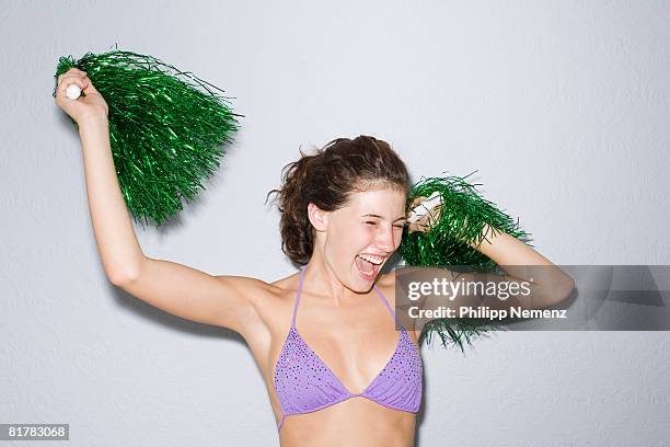 girl in purple bikini top, cheering with green pom - white pom pom stock pictures, royalty-free photos & images