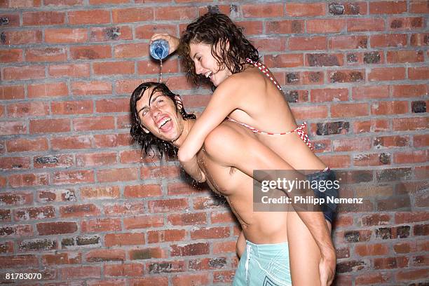 young couple, girl piggyback splashing water on her friend - philipp nemenz stock-fotos und bilder