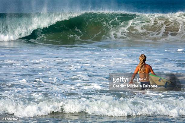 young man entering surf on pacific coast - puerto escondido stock pictures, royalty-free photos & images