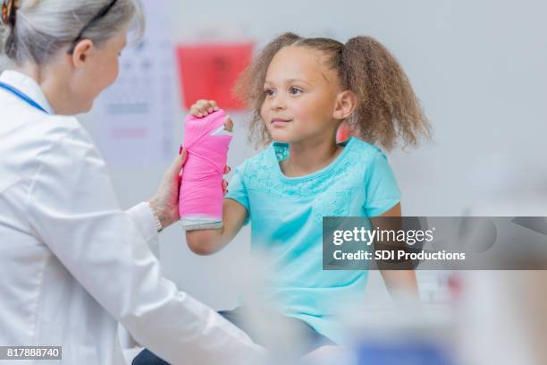 young patient holds up broken arm - orthopedic equipment stock pictures, royalty-free photos & images