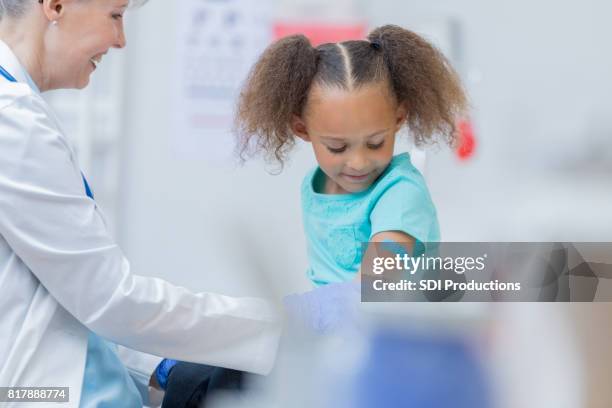 la bambina riceve il vaccino presso lo studio medico - vaccino antinfluenzale foto e immagini stock