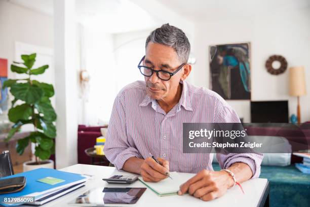 mature man doing working at home - economía fotografías e imágenes de stock