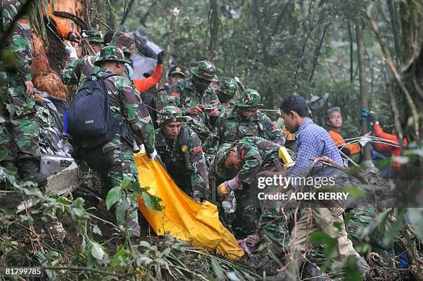 Indonesian soldiers and volunteers remove a victims's body from the crashed military plane Casa C-212 at a jungle of Salak mountain of Bogor district...