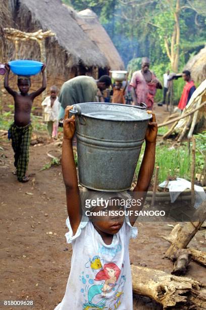 Des enfants reviennent du point d'eau le 17 novembre 2001 dans le camp de réfugiés de Boedu, fief de la rébellion armée sierraléonaise du Front...