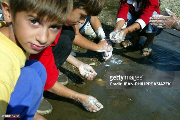 Des enfants se lavent les mains dans une flaque d'eau, le 17 septembre 2002 dans un bidonville à Vaulx-en-Velin. Le bidonville où vivaient des...