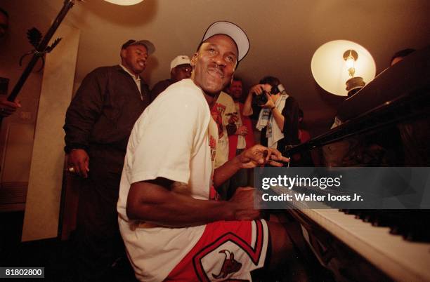 Basketball: NBA finals, Closeup of Chicago Bulls Michael Jordan victorious playing piano and smoking cigar in hotel after winning game and...