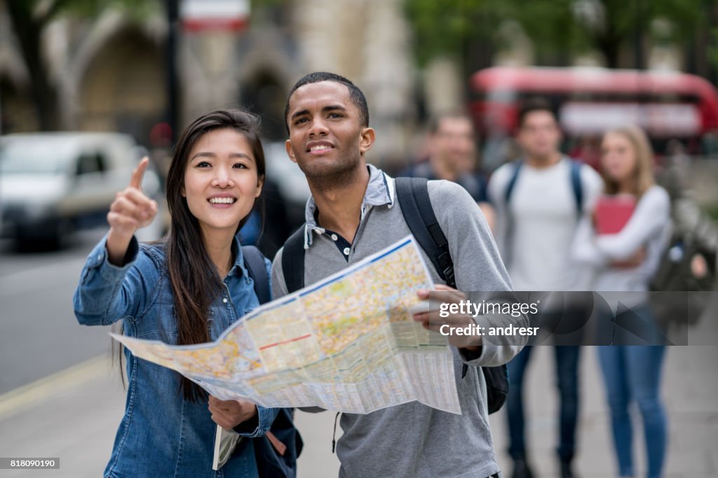 Happy students sightseeing in London and holding a map