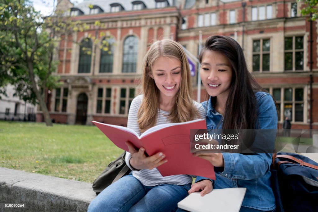 Happy female students studying outdoors