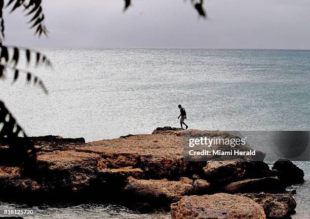 Boy walks along the shore in Port Salut, Haiti in late June, nearly nine months after Hurricane Matthew struck the area.