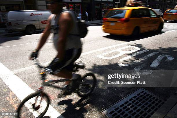 Man rides down a city street July 3, 2008 in New York City. Party due to the rise in fuel prices, the use of scooters and bicycles for New York...