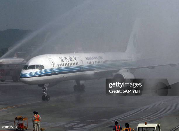 The Xiaman Airline plane carrying the first group of Chinese tourists to arrive in Taipei from Xiamen, goes through a welcome water fountain provided...