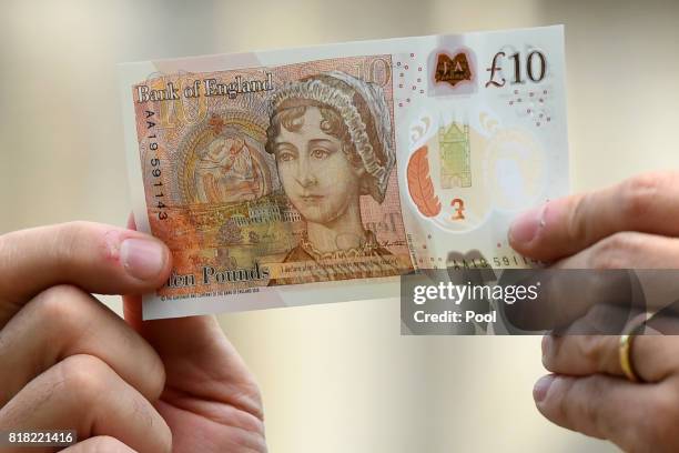 Bank of England Governor Mark Carney poses with one of the central bank's new ten pound notes, featuring British author Jane Austen, during its...