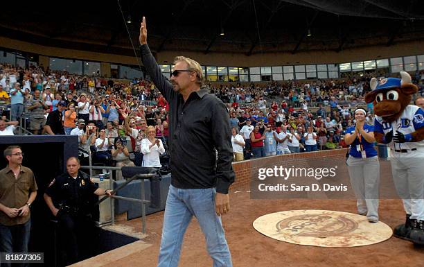 Kevin Costner waves to fans as he arrives for his concert with his band Modern West at a July Fourth celebration at the Durham Bulls Athletic Park in...