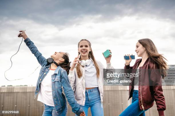 drie tienermeisjes nemen juichende buitenshuis - sing outside stockfoto's en -beelden