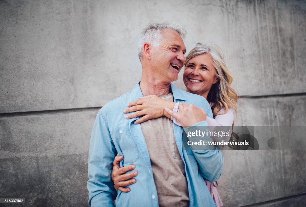 Senior married couple hugging and laughing together on city break