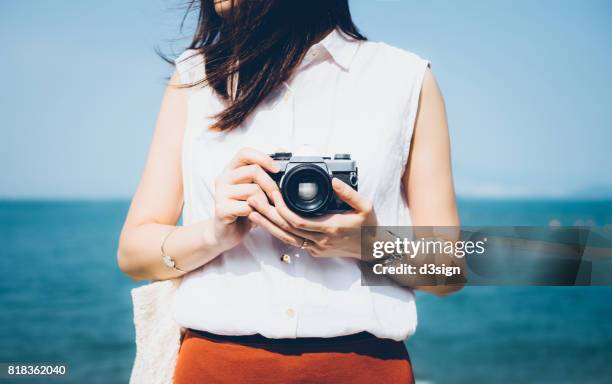 girl taking photos with vintage film camera in the beach on a sunny day - retro camera stock pictures, royalty-free photos & images