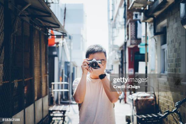 young man taking photos with retro film camera in city street - old photographer stock pictures, royalty-free photos & images