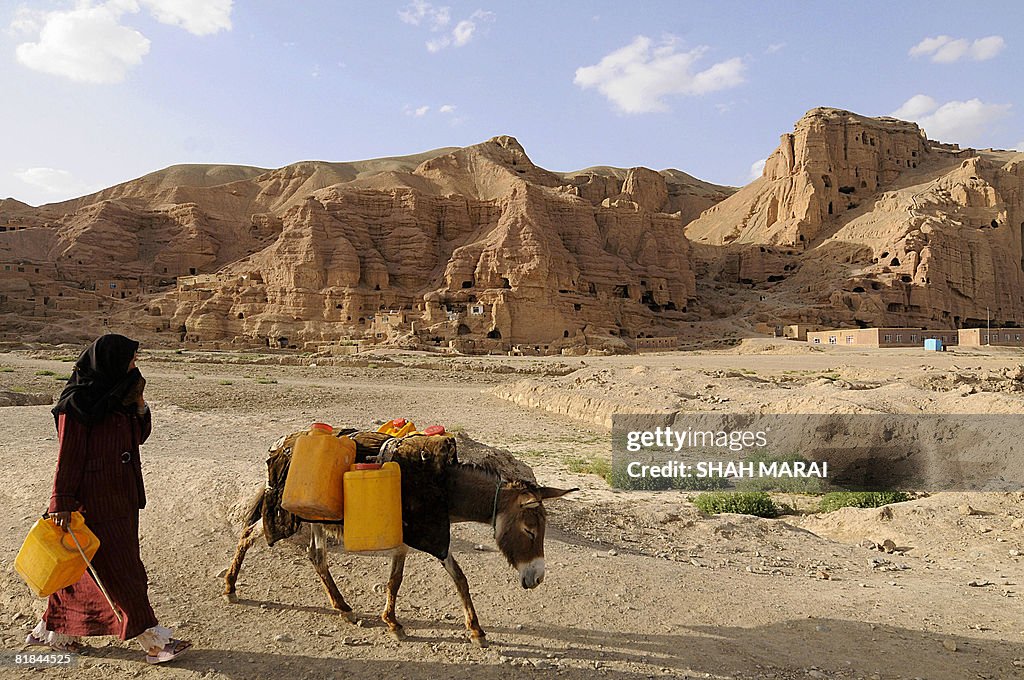 An Afghan woman leads her donkey loaded