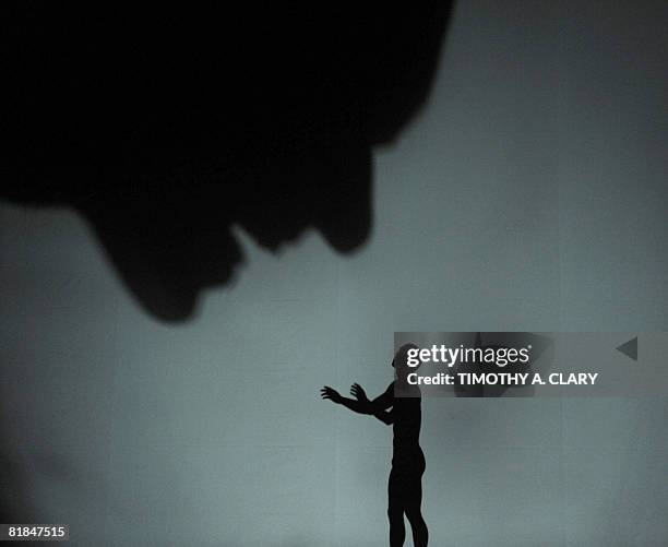 Using a rear-projection screen to display their dance movements, the modern dance group Pilobolus perform "Darkness and Light" during a dress...