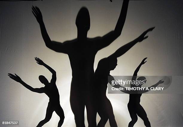 Using a rear-projection screen to display their dance movements, the modern dance group Pilobolus perform "Darkness and Light" during a dress...