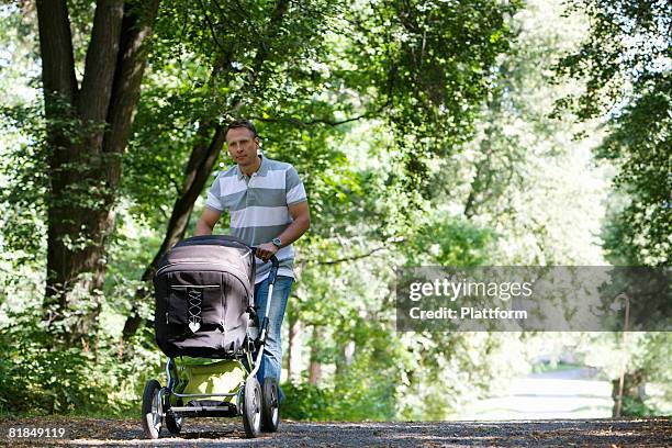 father walking in a park with a pram a sunny day sweden. - vaterschaft stock-fotos und bilder