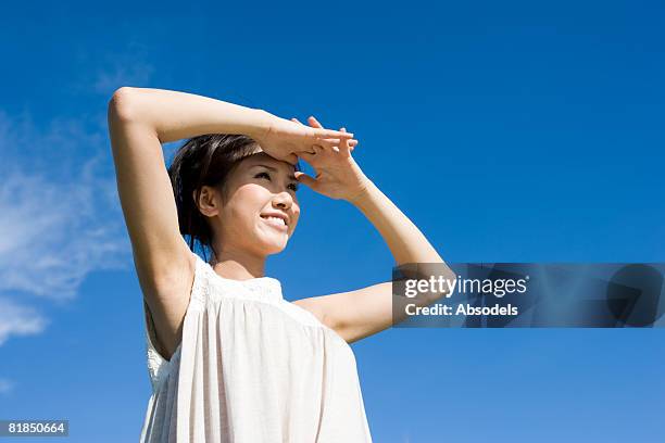 young woman shielding her eyes and looking at view - arms raised to sky stock pictures, royalty-free photos & images