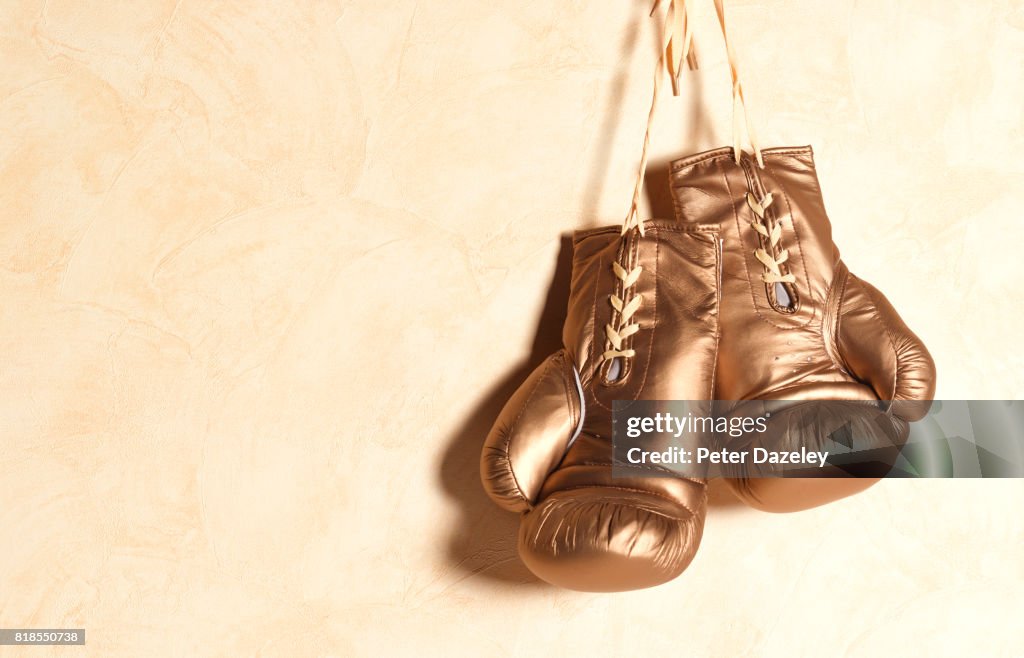 Gold boxing gloves hanging with copy space