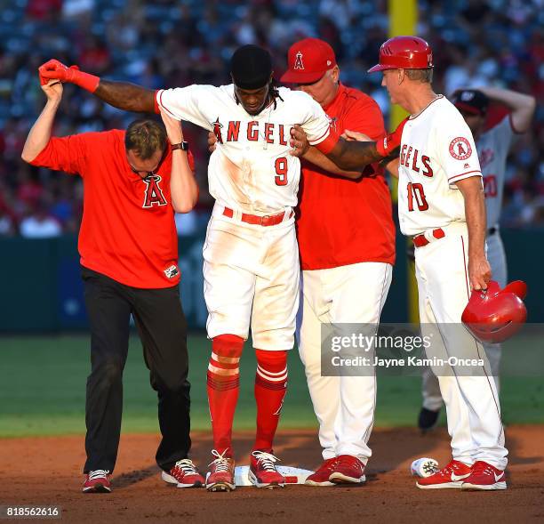 Cameron Maybin of the Los Angeles Angels of Anaheim is helped off the field by Ron Roenicke Mike Scioscia and and trainer Adam Nevala after injuring...