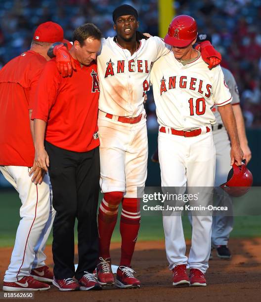 Cameron Maybin of the Los Angeles Angels of Anaheim is helped off the field by Ron Roenicke and trainer Adam Nevala after injuring his knee...