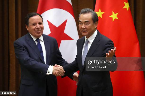 Tunisia's Foreign Minister Khemaies Jhinaoui, left, and Chinese Foreign Minister Wang Yi, right, shake hands as they pose for a photo before a...