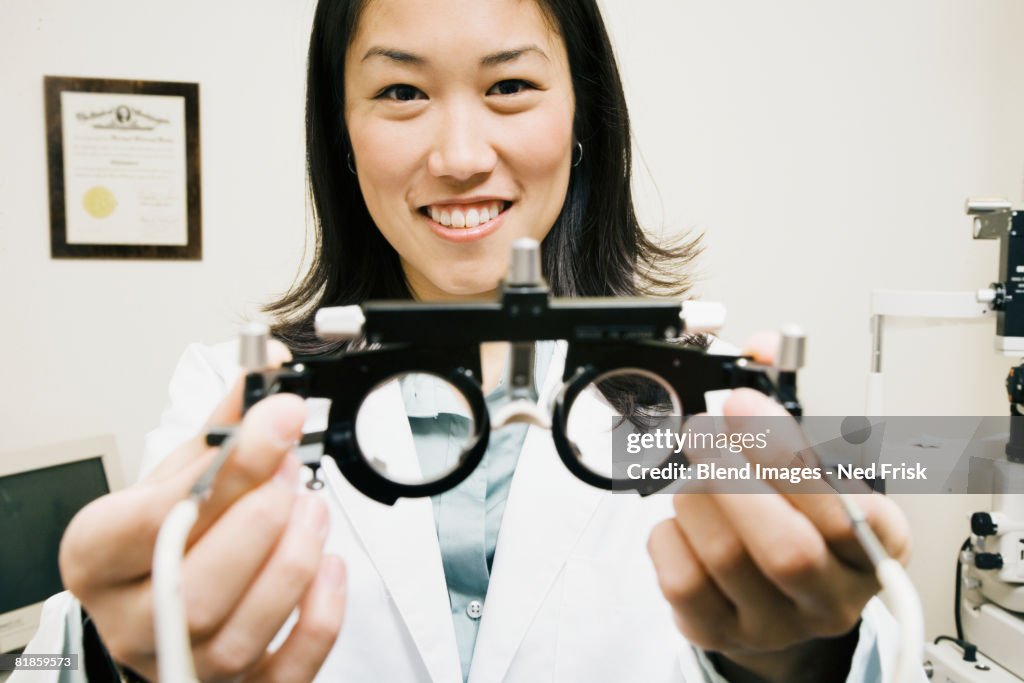 Asian female optometrist holding equipment