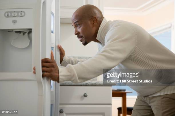 african man looking in refrigerator - open grave stock pictures, royalty-free photos & images